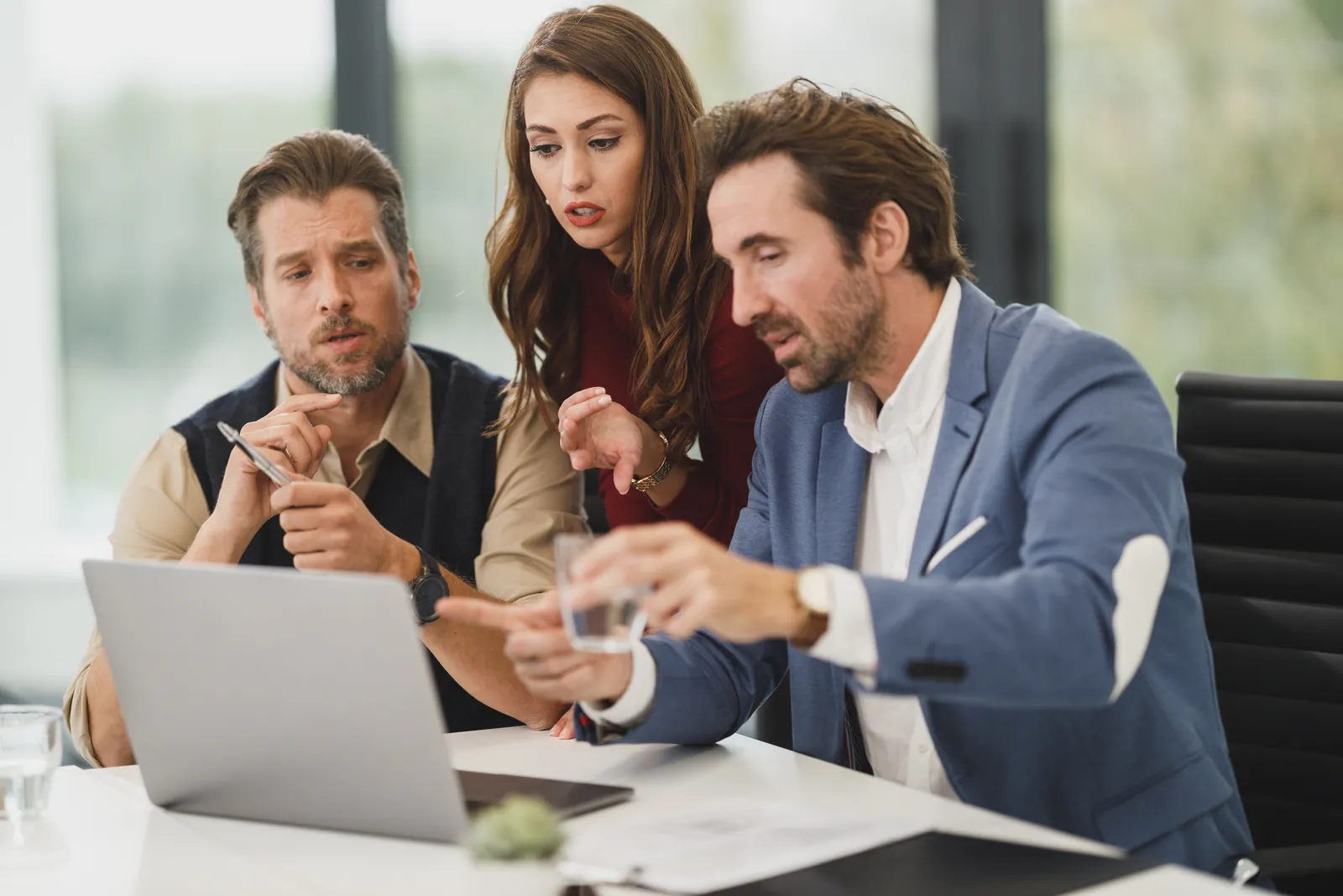 Tres profesionales revisando juntos información en un computador portátil